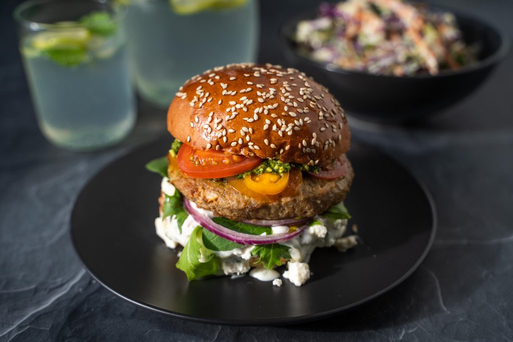 Lamb burger with lettuce, tomatoes, tzatziki and red onion served with coleslaw and sparkling water