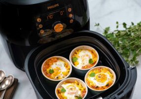 Four Mac and cheese and half baked egg ramekins with oregano leaves cooked in a Philips Premium Airfryer